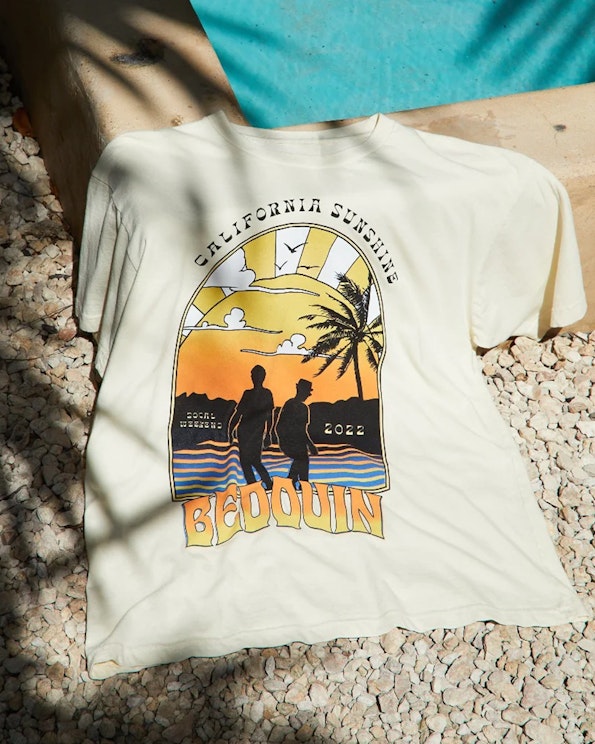 Screen printed cream cotton graphic tee with retro sunset beach scene and palm tree art, produced by MerchCamp for Bedouin