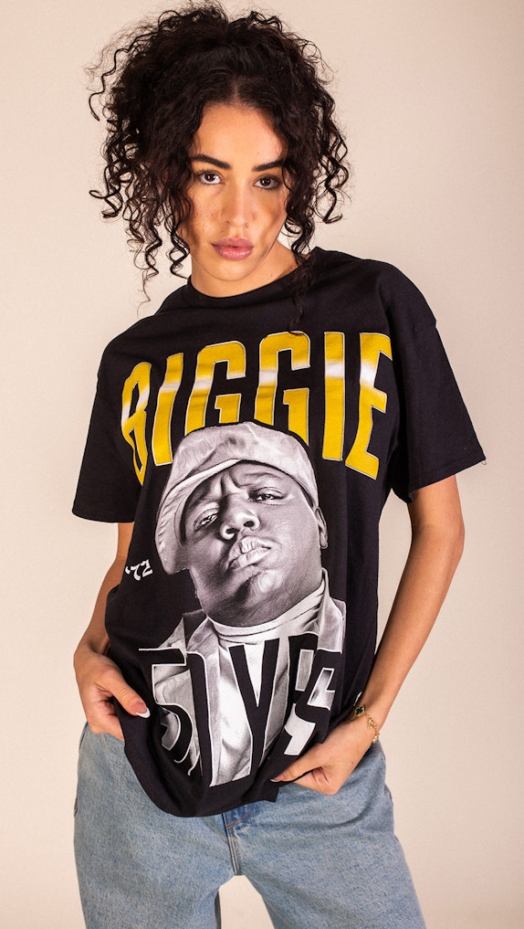 Woman modeling black Biggie Smalls graphic t-shirt paired with light blue jeans, custom merchandise by MerchCamp