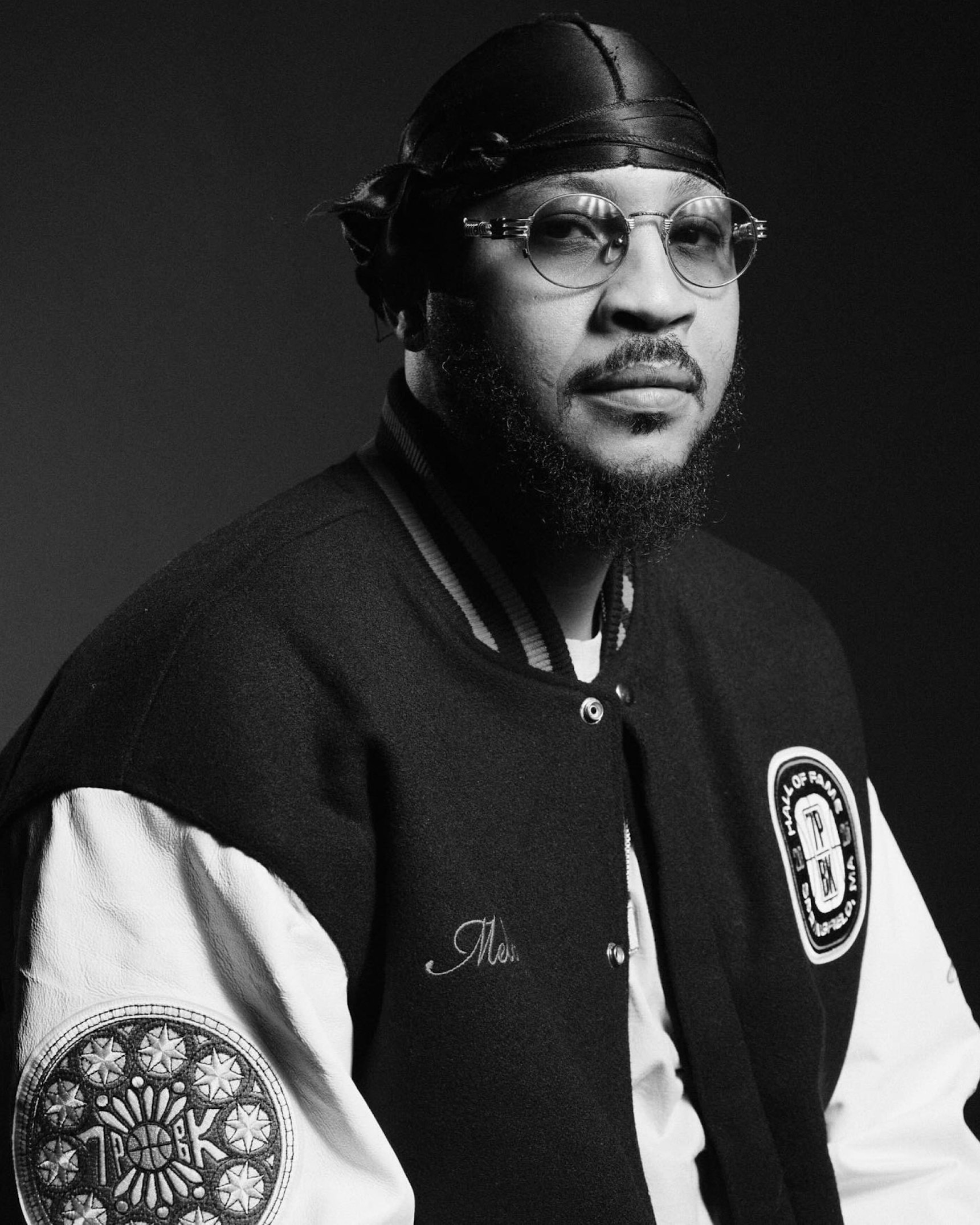 Black and white portrait of man wearing leather durag, glasses, and varsity — WAVE Sports + Entertainment merchandise by MerchCamp
