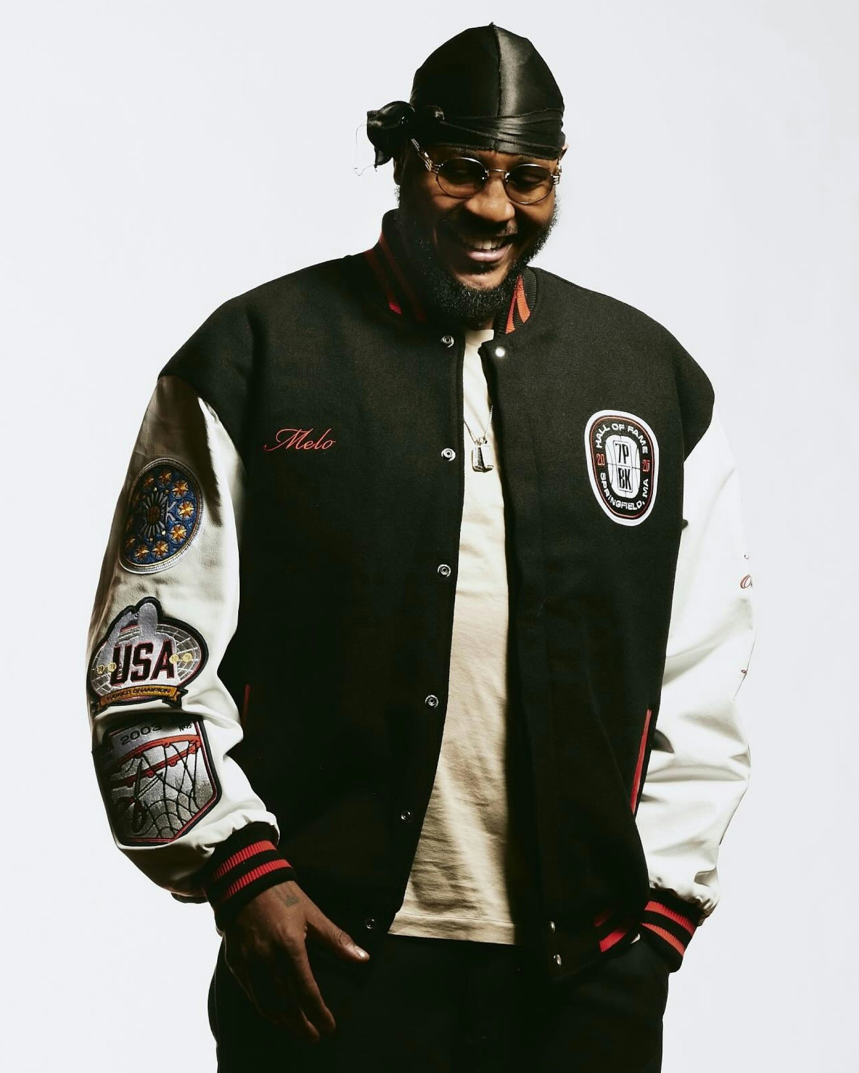 Smiling man in black and white varsity letterman jacket with Melo embroidery — WAVE Sports + Entertainment merchandise by MerchCamp