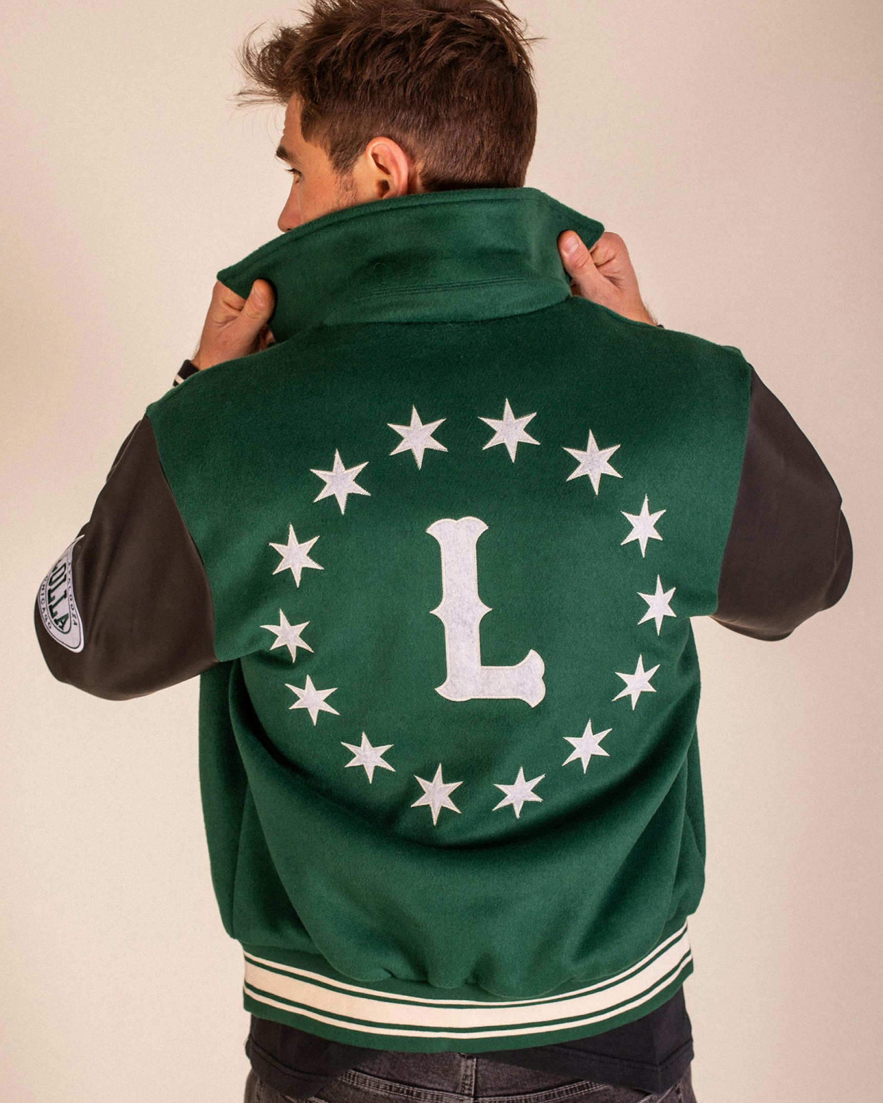 Man modeling green varsity letterman jacket with leather sleeves, star circle and L patch — Lollapalooza merchandise by MerchCamp