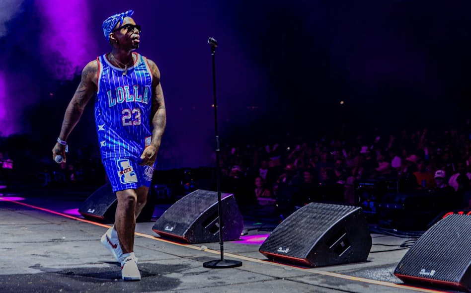 Performer on stage at Lollapalooza wearing custom blue number 23 Lolla basketball jersey with purple stage lighting, produced by MerchCamp for Lollapalooza