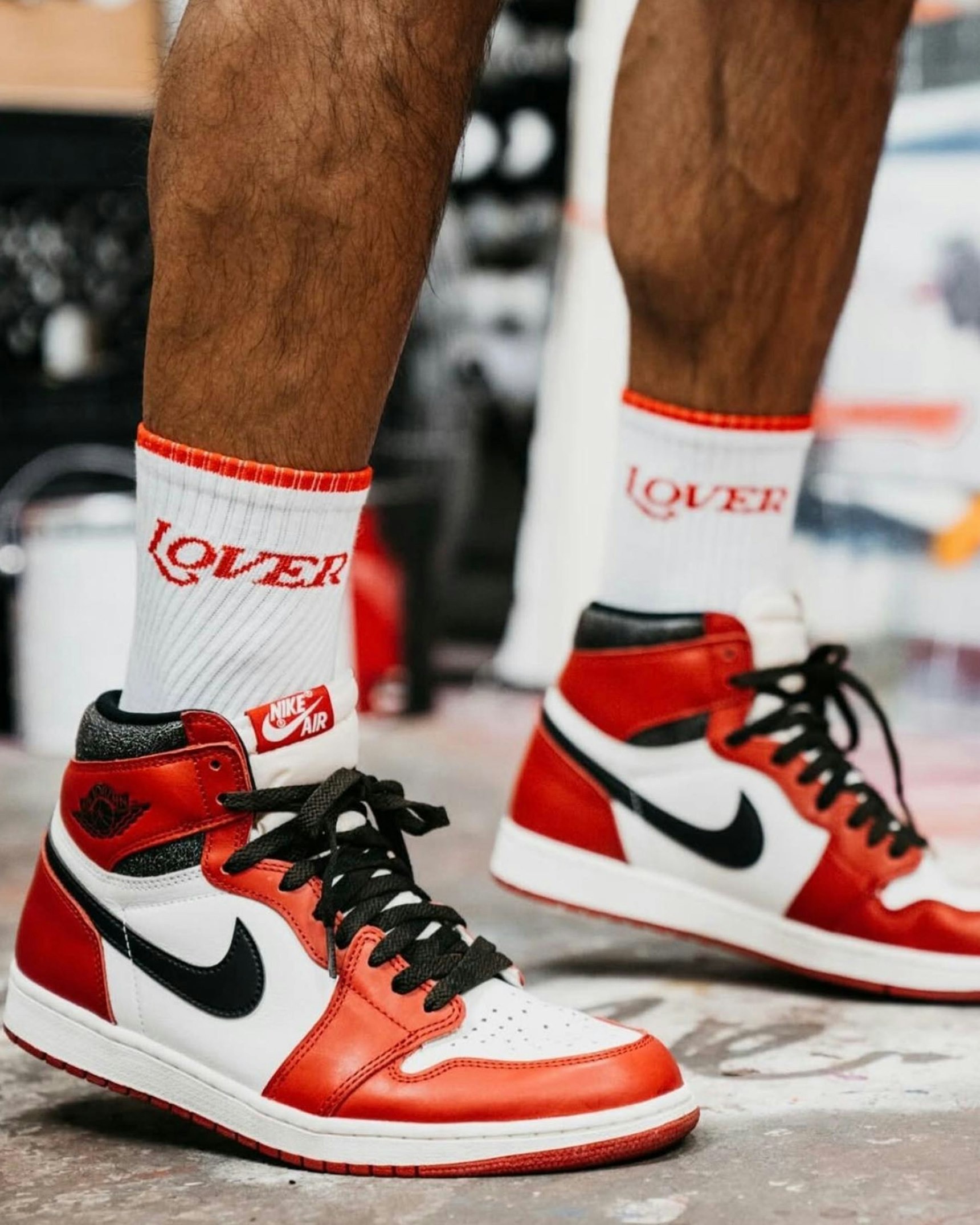 Person wearing red, white, and black Air Jordan 1 sneakers with white "Lover" socks — Ruben Rojas merchandise by MerchCamp