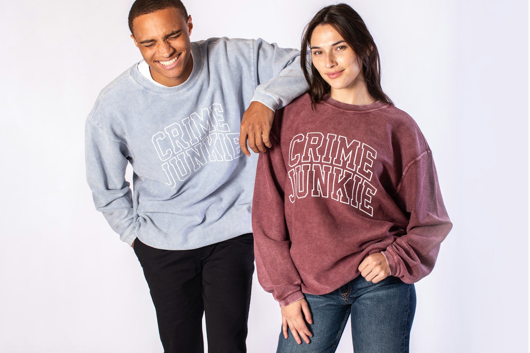 Two models wearing Crime Junkie collegiate-style corded sweatshirts in light blue and maroon — Crime Junkie merchandise by MerchCamp