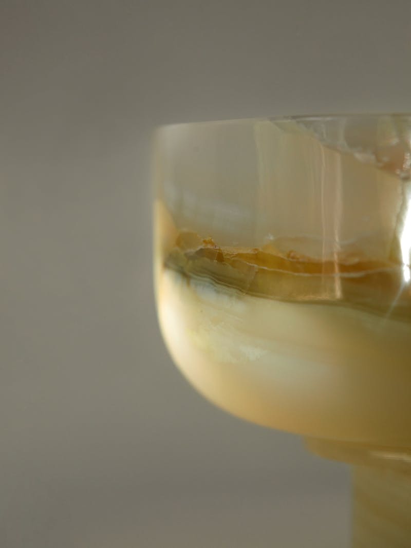 Detail image of an onyx bowl from Bloc Studios, a unique and hand made bowl from green, cream, amber and yellow polished stone. 