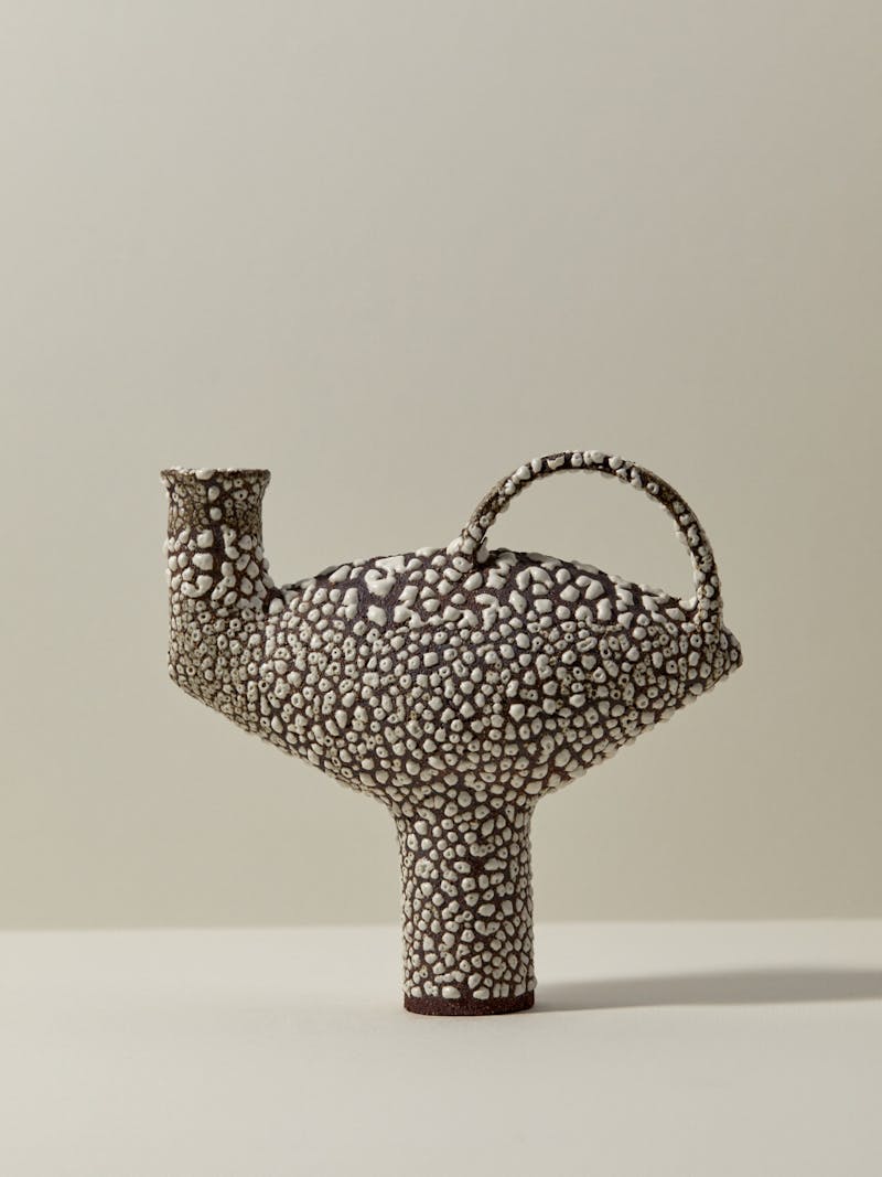 black and white textured glazed ceramic sculptural stoneware vessel by Catherine Dix. The body of the vessel is wide and oblong and the foot is narrow and long. 