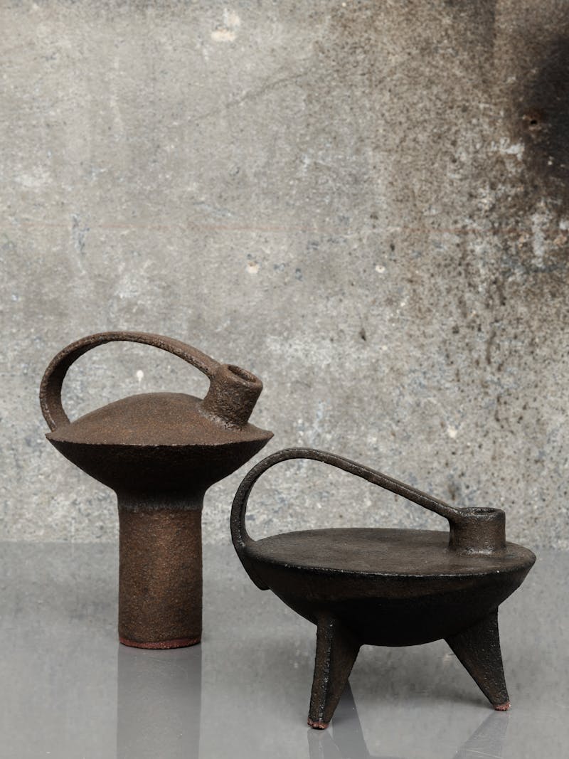 Colour image displaying Cocotte 07 in brown (left) and Cocotte 10 in black (right) by Catherine Dix, made from red stoneware clay. These unique, ceramic sculptures are part of the new 2024 spring collection 'Observations' by online gallery Metamorphoses Objects.