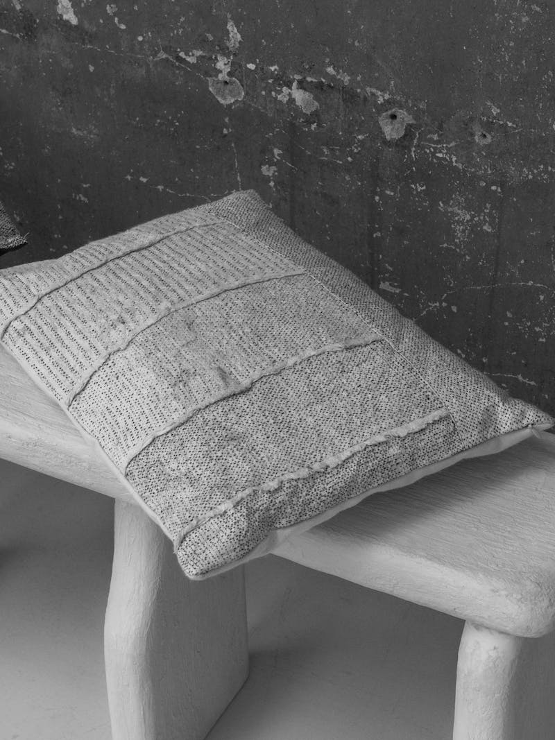 Black and white image displaying Wooden Textile Pillow in grey by material studio Buro Belén. This unique, homeware item is part of the new 2024 spring collection 'Observations' by online gallery Metamorphoses Objects. 