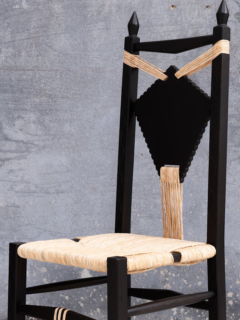 Colour image displaying the Ines Chair from the 'scannu' series by Pretziada. The material is made from chestnut wood and contains woven beige-coloured decorative elements. This furniture object is part of the new 2024 spring collection 'Observations' by online gallery Metamorphoses Objects. 