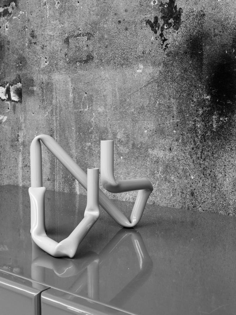 Black and white image of the handmade Bucatini aluminium candle holder in shiny beige by Danish design studio A.O.T. The object is part of the new 2024 spring collection 'Observations' by online gallery Metamorphoses Objects.