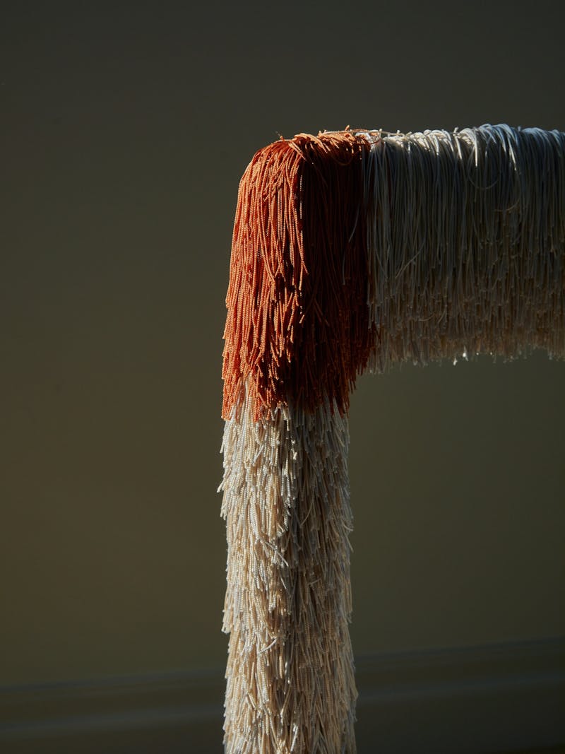 detail of a fringed wool chair by Amsterdam based design studio Buro Belen. Colours of the fringe include orange, cream and blue. 