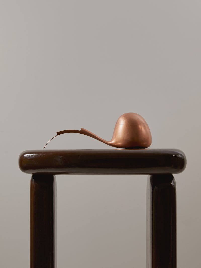 copper and silver curved soy pouring vessel with a long sculptural neck and rounded dome like body. The pourer is shown on the Bo Bardi Side Table by Destroyers/Builders and is made by Dutch designer Aldo Bakker. 