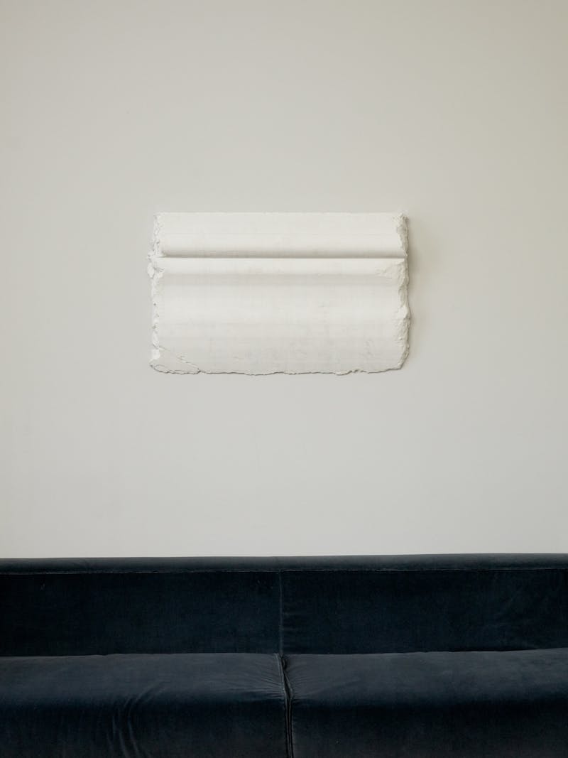 Handmade object - limited edition wall mounted plaster architectural moulding white relief sculpture by Romy Yedida, Israeli artist and designer working in Amsterdam.  Cornice is hung over a blue velvet couch.