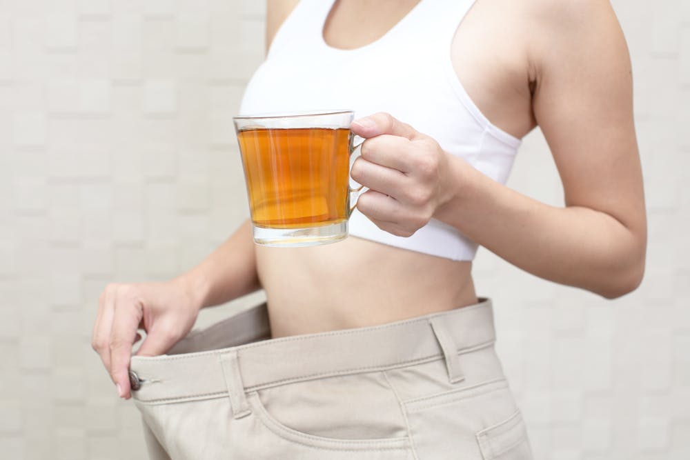 A lady checking the effect of slimming tea on her weight