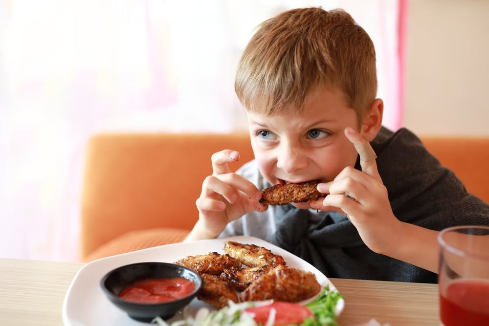 A boy eating grilled chicken KFC