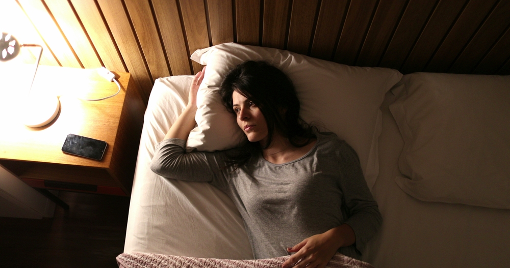 Person lying awake in bed at night
