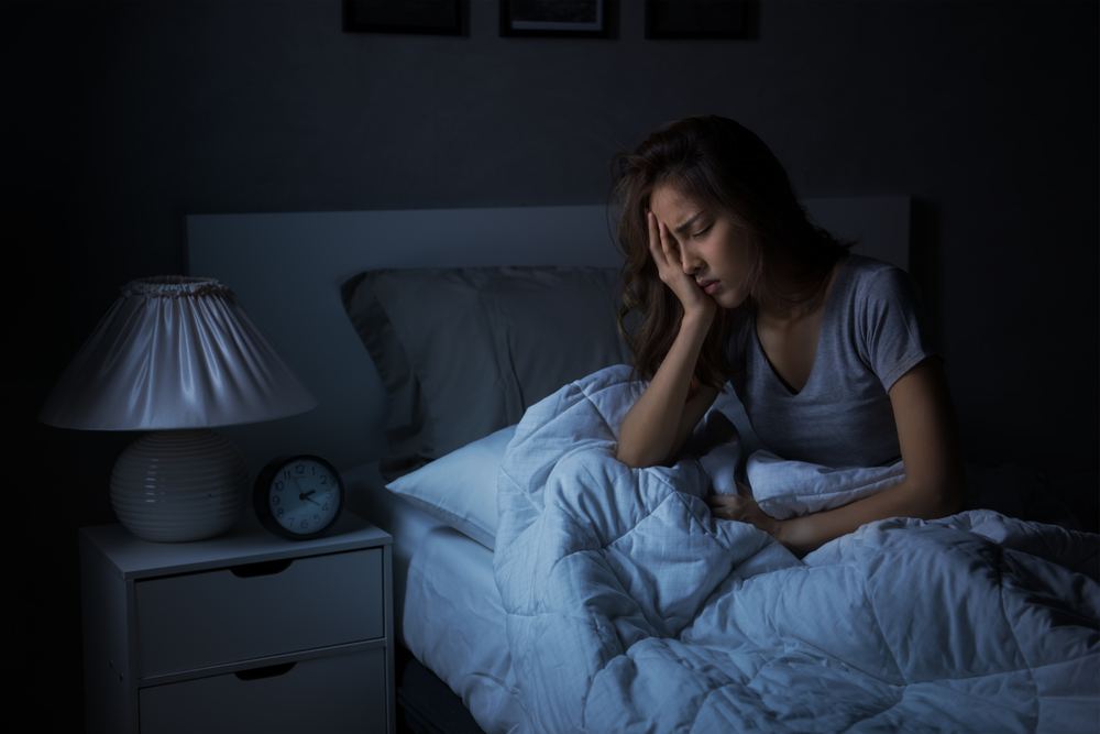 Stressed woman lying awake in bed at night