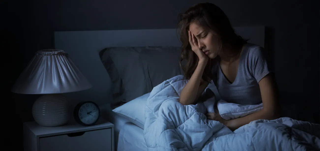 Stressed woman lying awake in bed at night