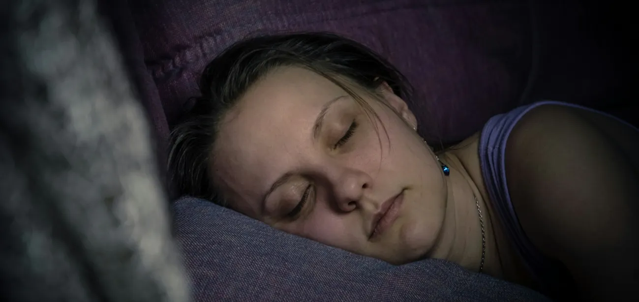 Person sleeping peacefully in a dark bedroom