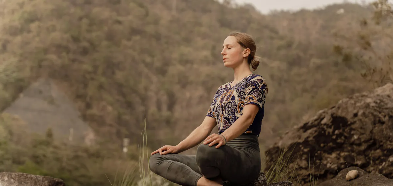 Woman meditating in nature to reduce stress and reverse aging