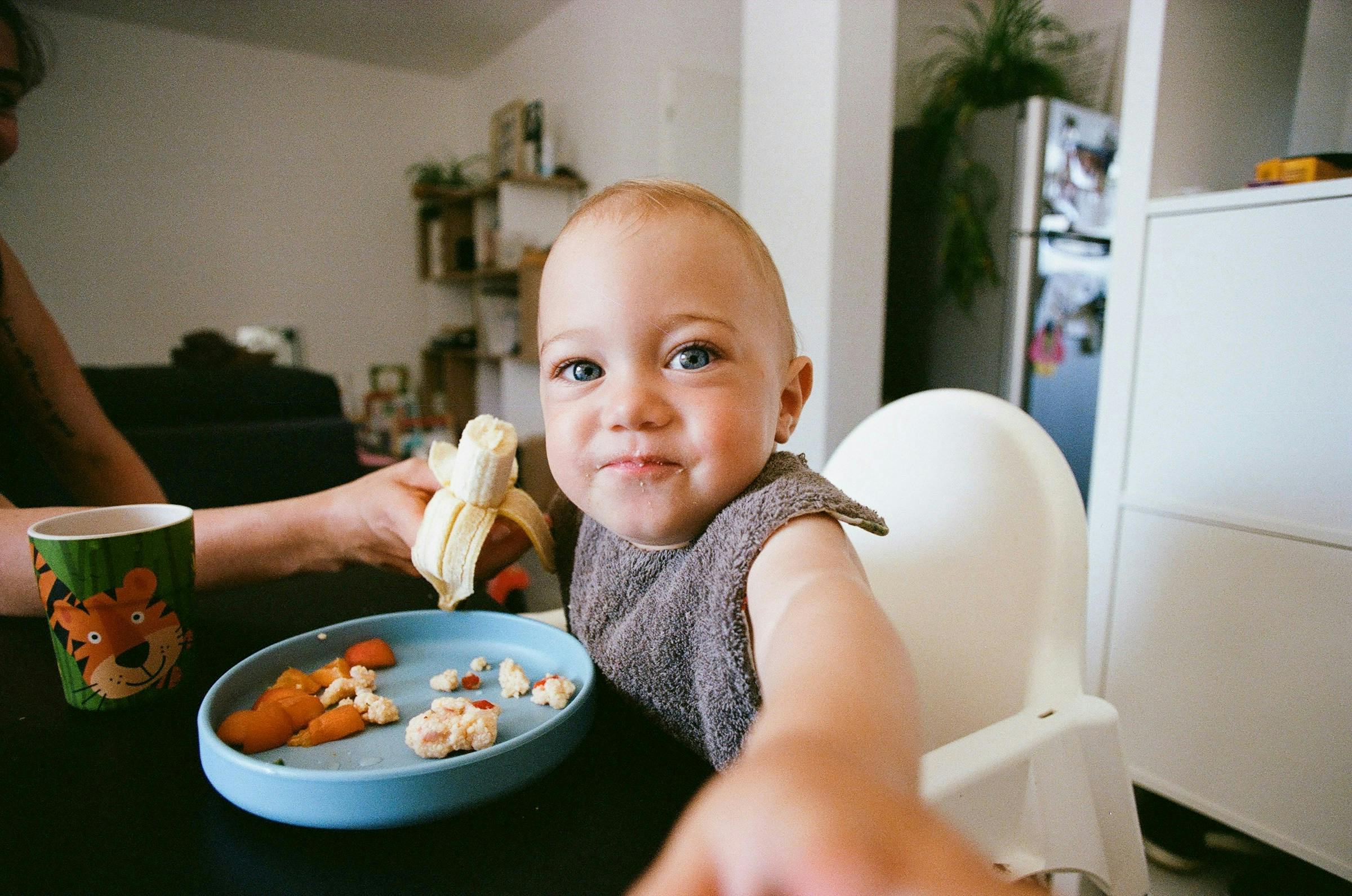 A baby eating banana and oatmeal breakfast – low-calorie carb meal idea