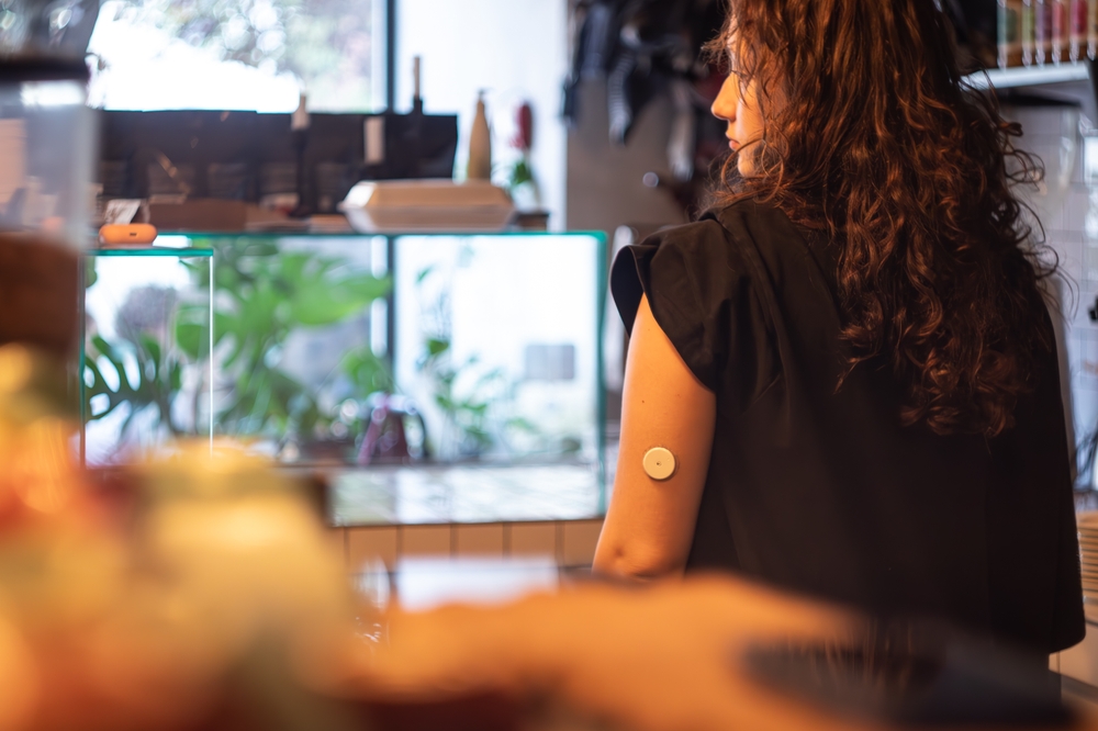 A person wearing a CGM on their arm