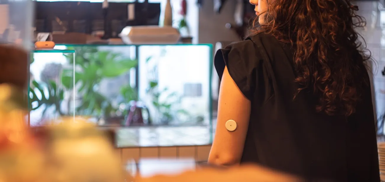 A person wearing a CGM on their arm