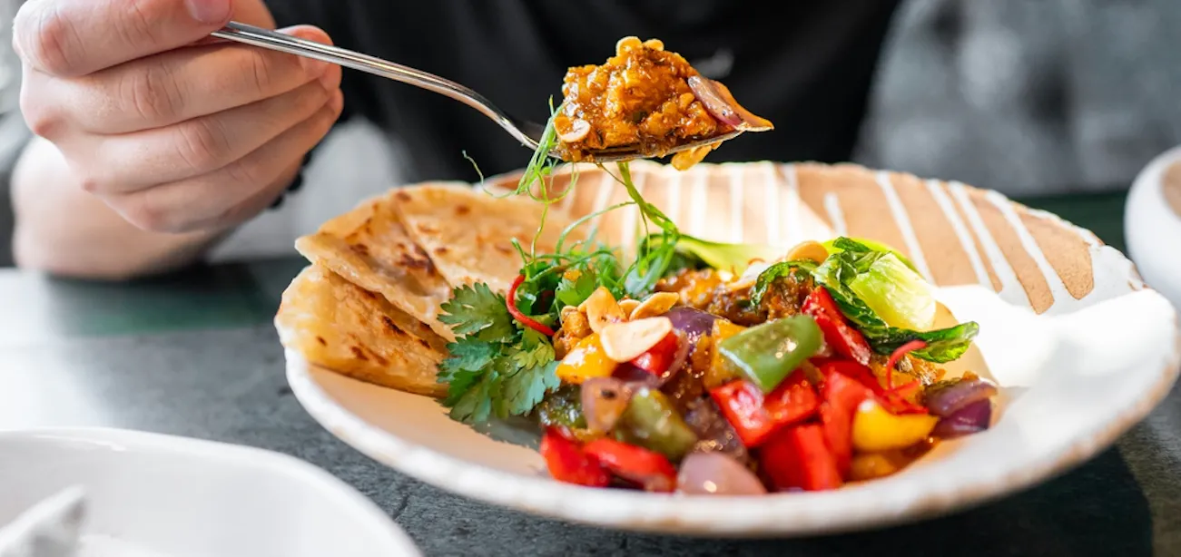 Person eating a healthy Indian meal at the restaurant