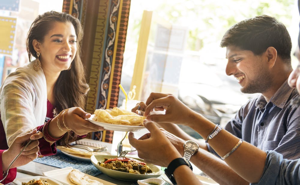 Friends enjoying healthy Indian restaurant dishes