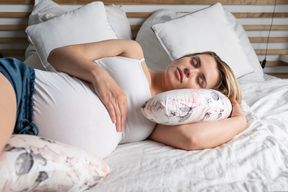 Pregnant woman sleeping on her left side with a body pillow