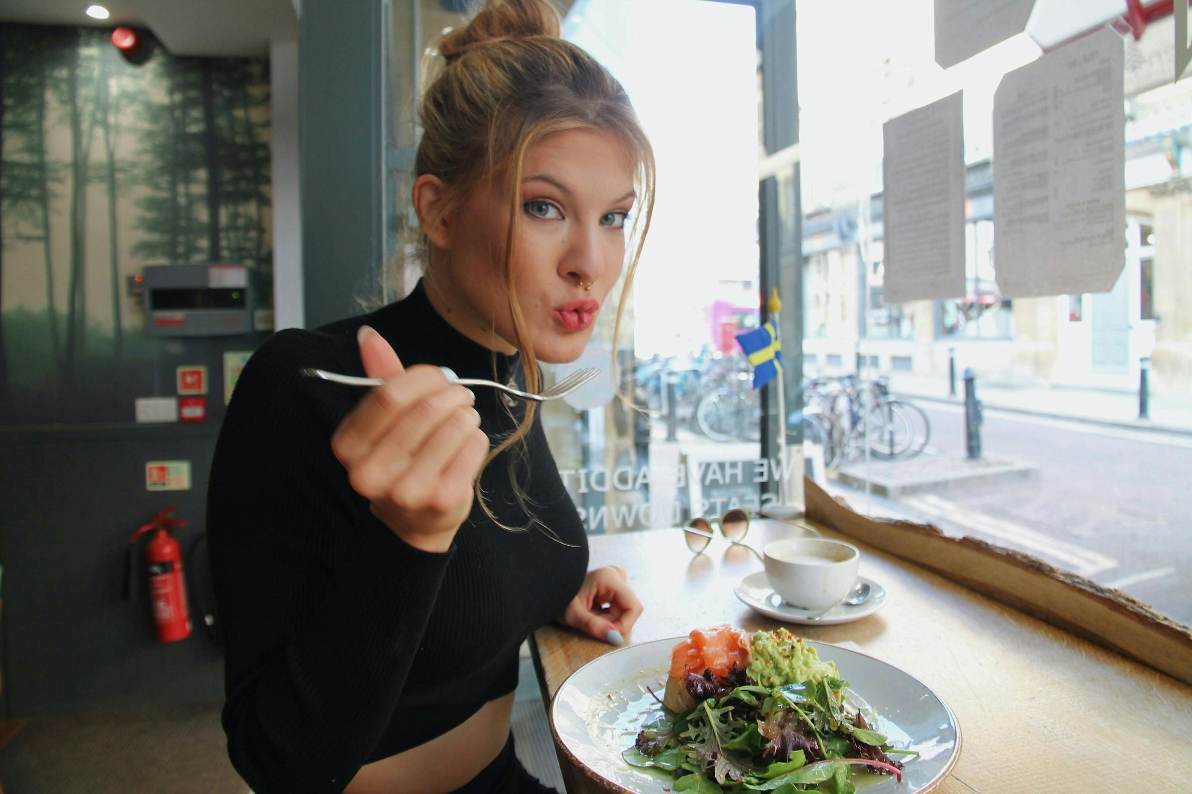 A lady eating Avocado toast with eggs at a brunch café