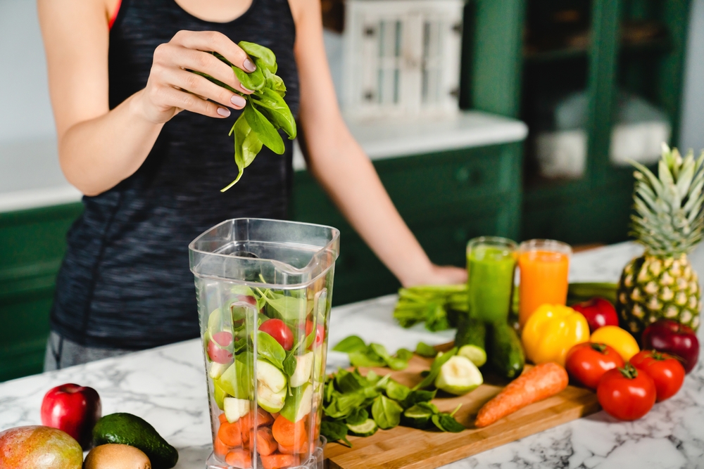 A lady preparing a smoothie with carotenoid-rich veggies and fruits