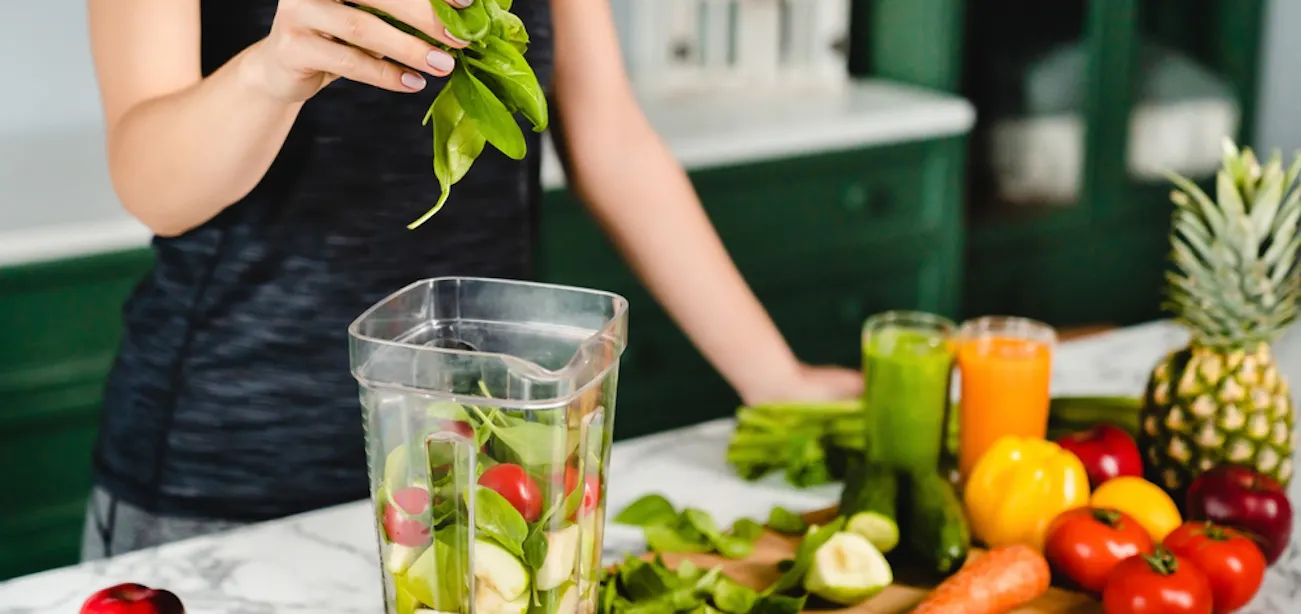 A lady preparing a smoothie with carotenoid-rich veggies and fruits
