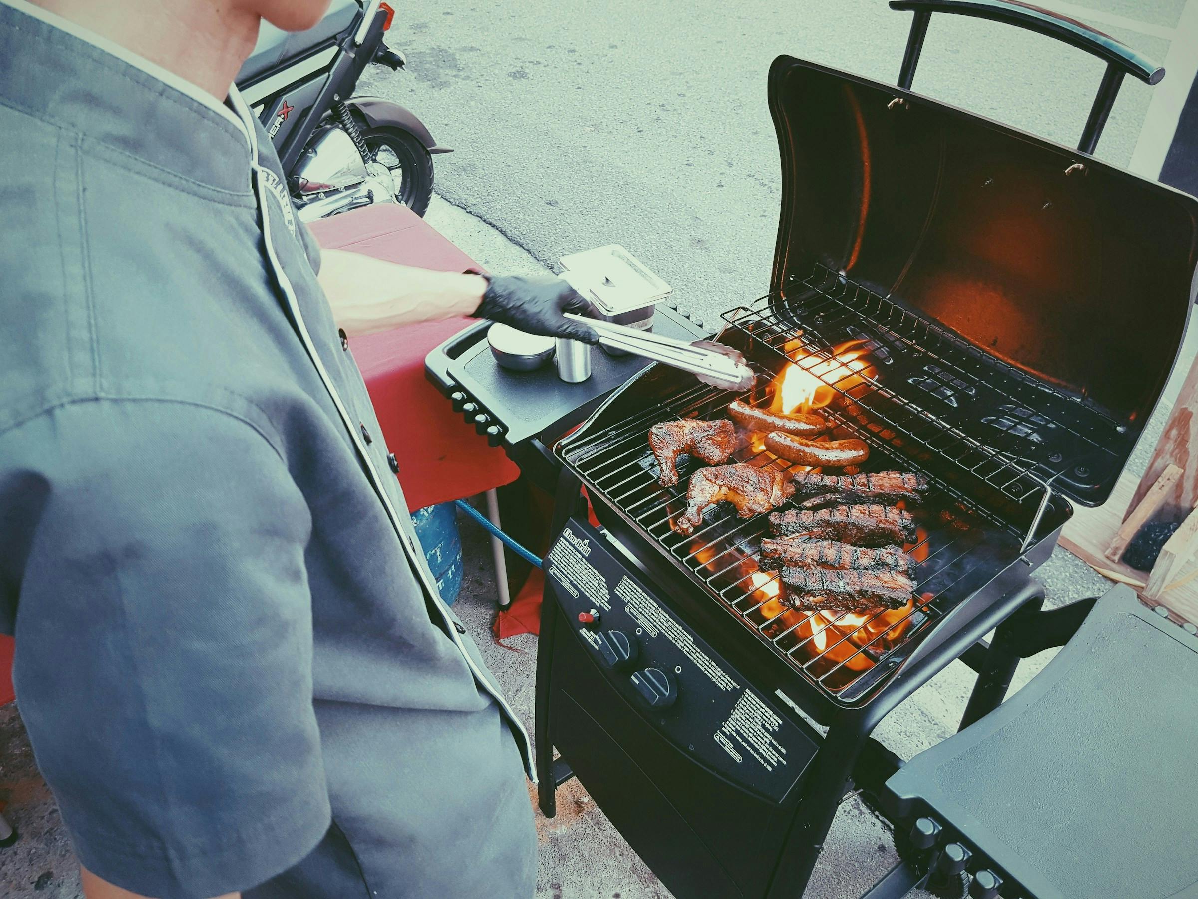 A person grilling both chicken and beef