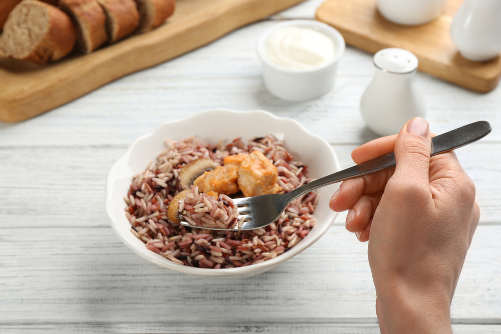 A person eating a meal of brown rice