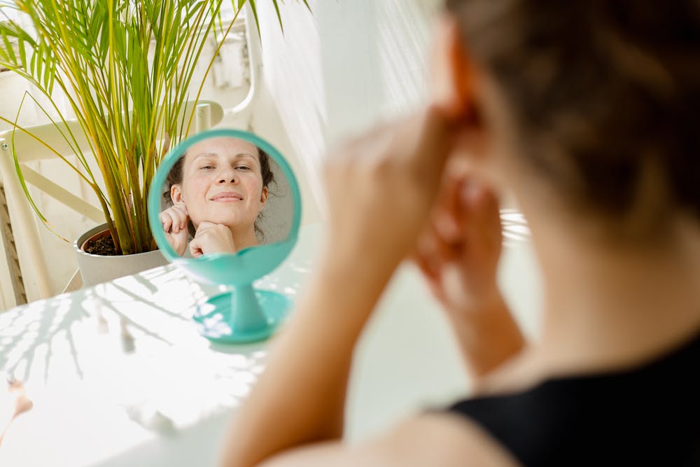 A woman checking her skin losing collagen