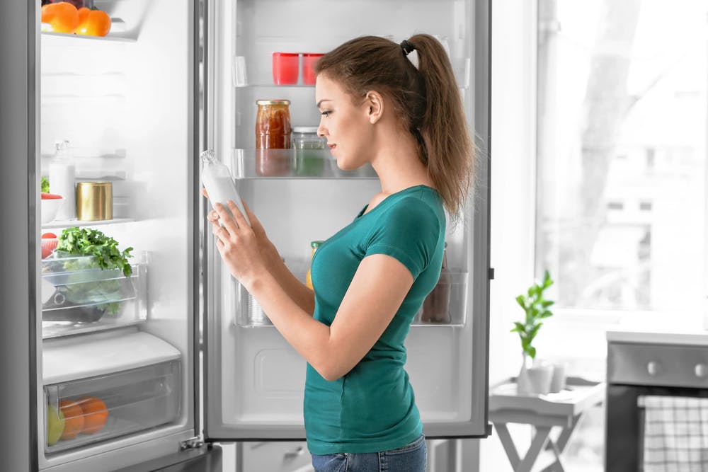 A lady taking coconut milk from the fridge