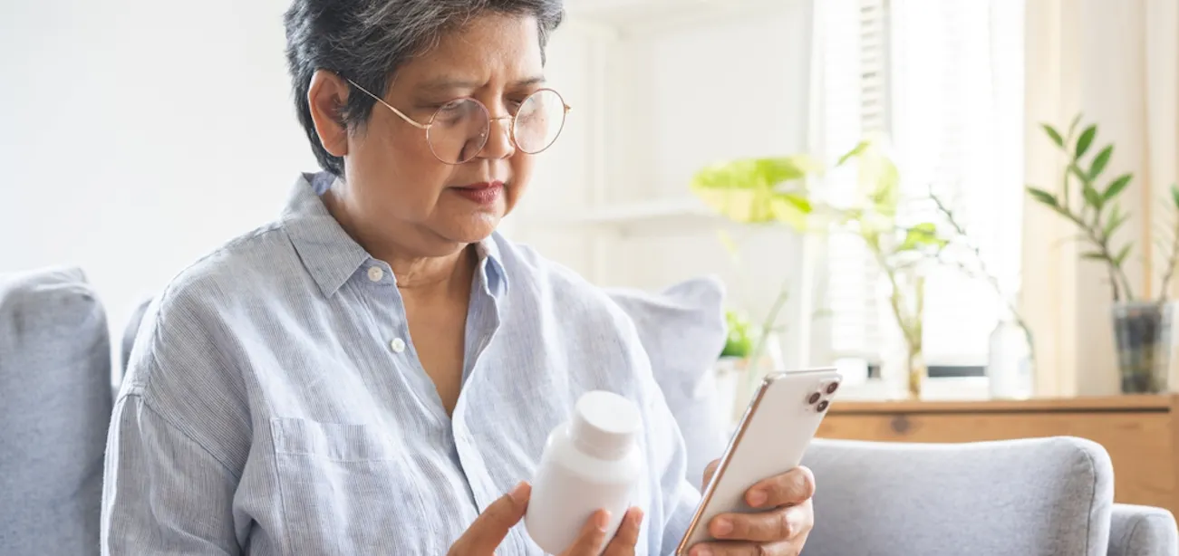 A woman with high folate levels from excess folic acid supplements checking her pill bottle