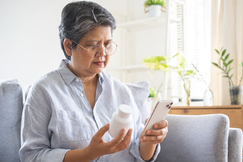 A woman with high folate levels from excess folic acid supplements checking her pill bottle