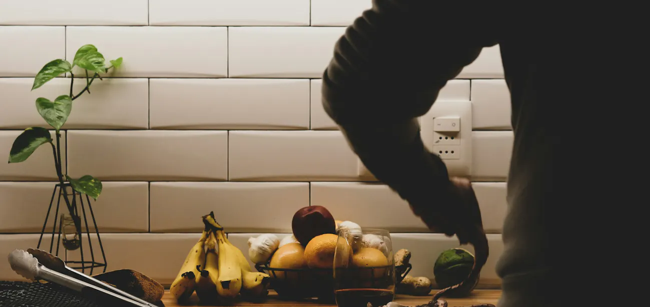 A man preparing a low carb food including eggs, fish, nuts, cheese, and leafy greens