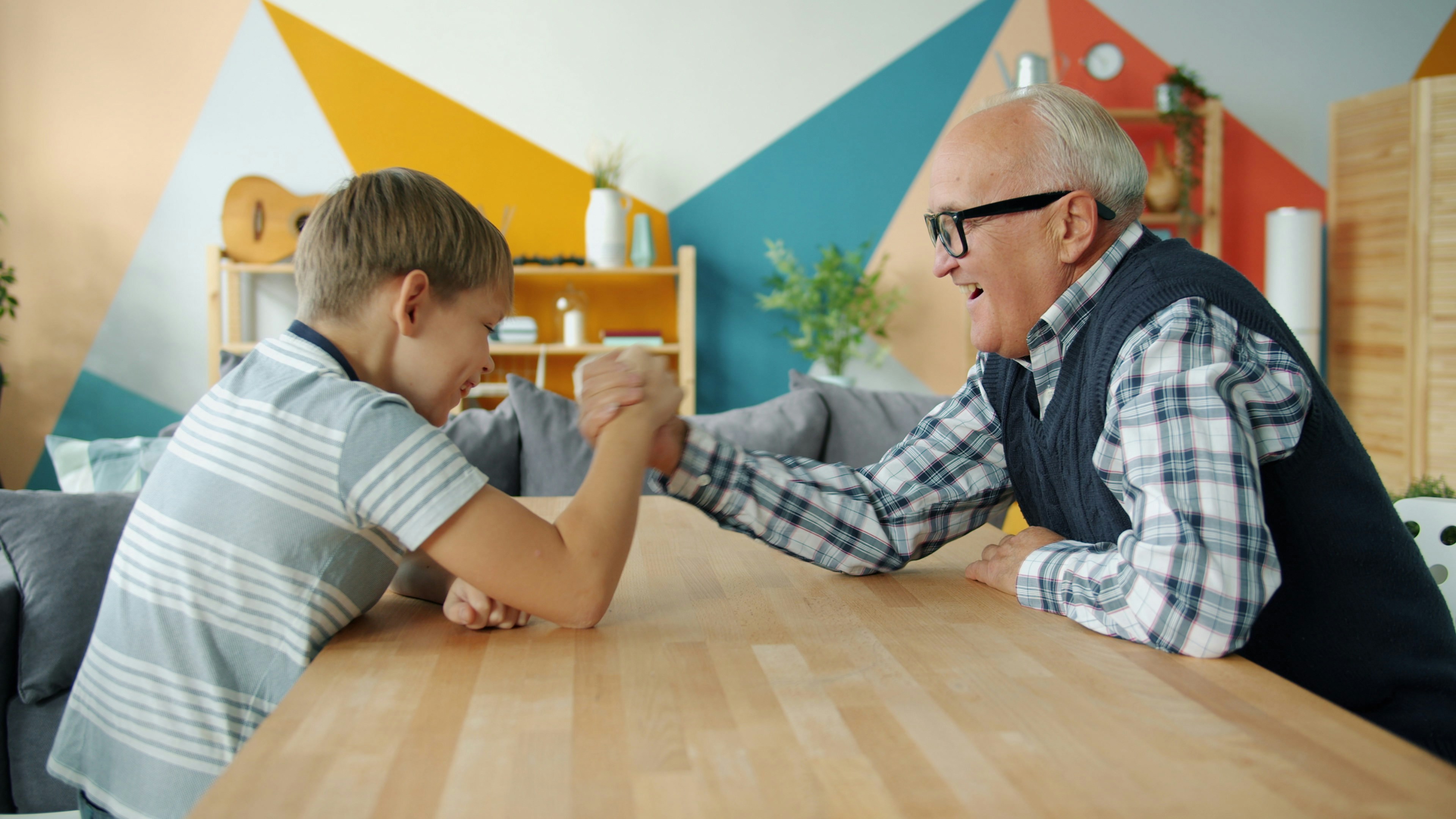 An image showing a growing boy and his granddad arm wrestling