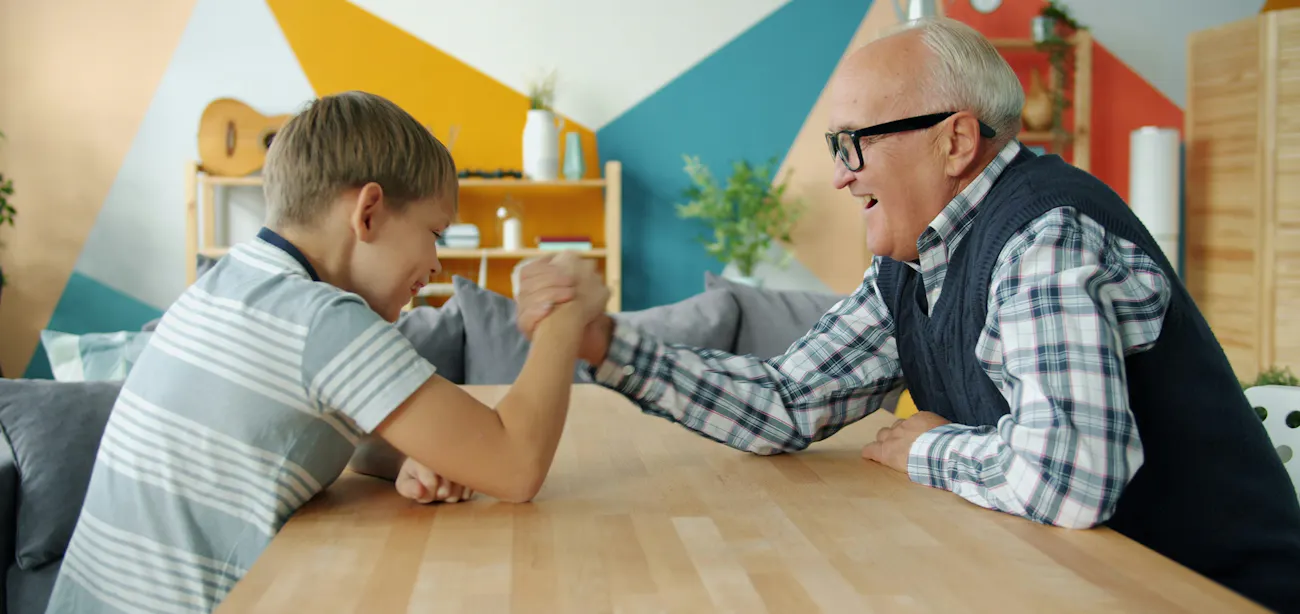 An image showing a growing boy and his granddad arm wrestling