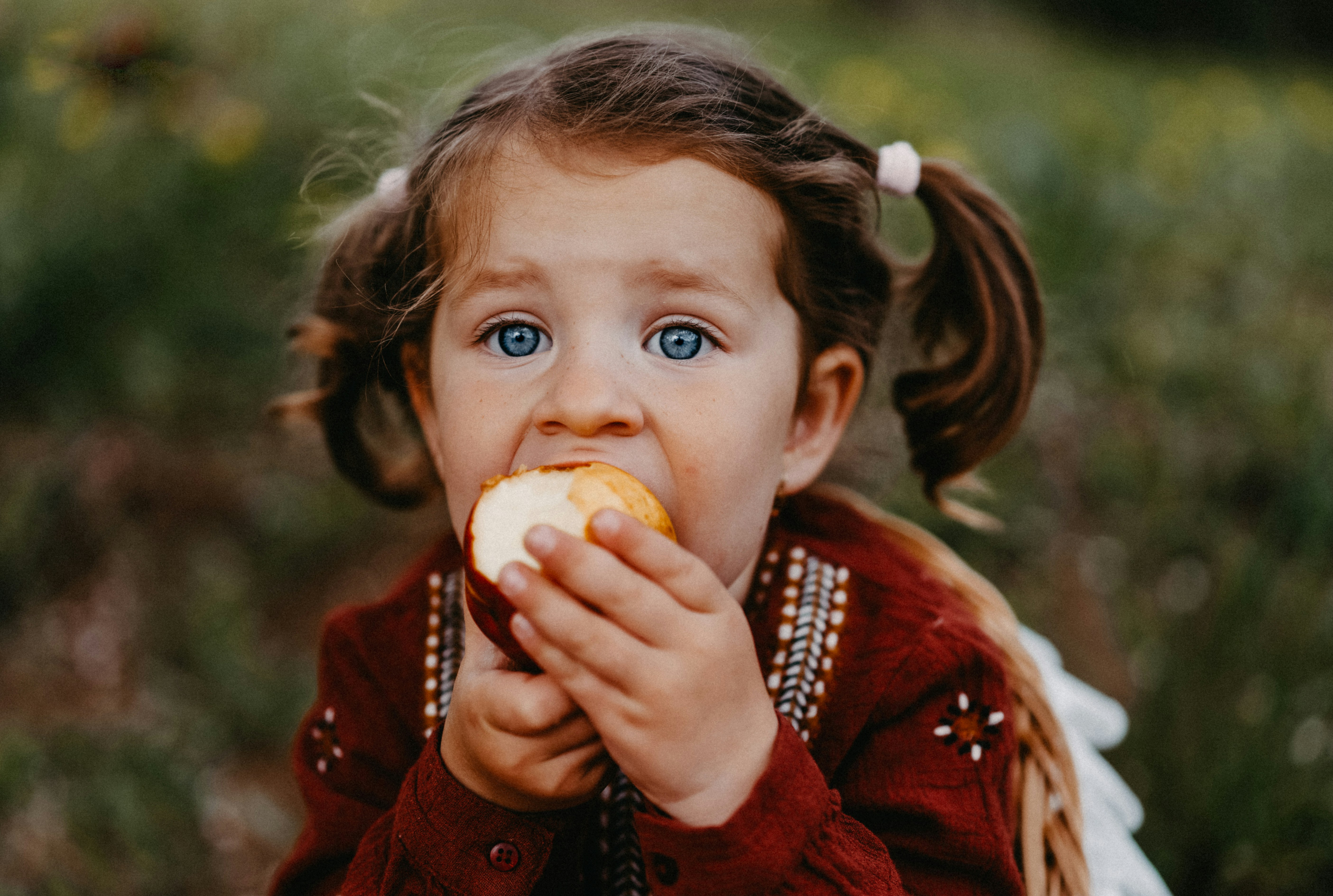 An image showing a pretty baby eating a fruit