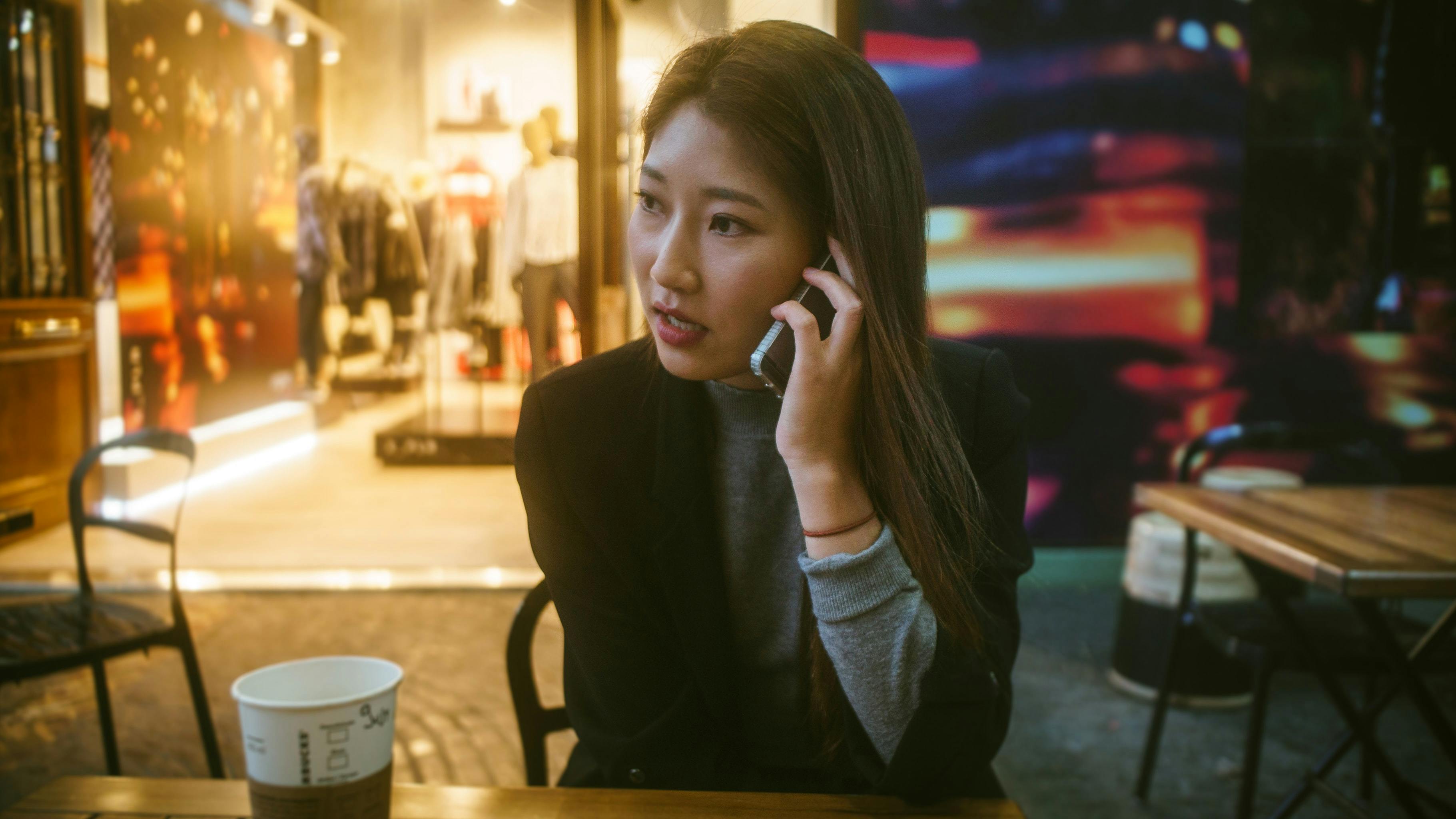 Woman sitting at a cafe patio talking on a cell phone