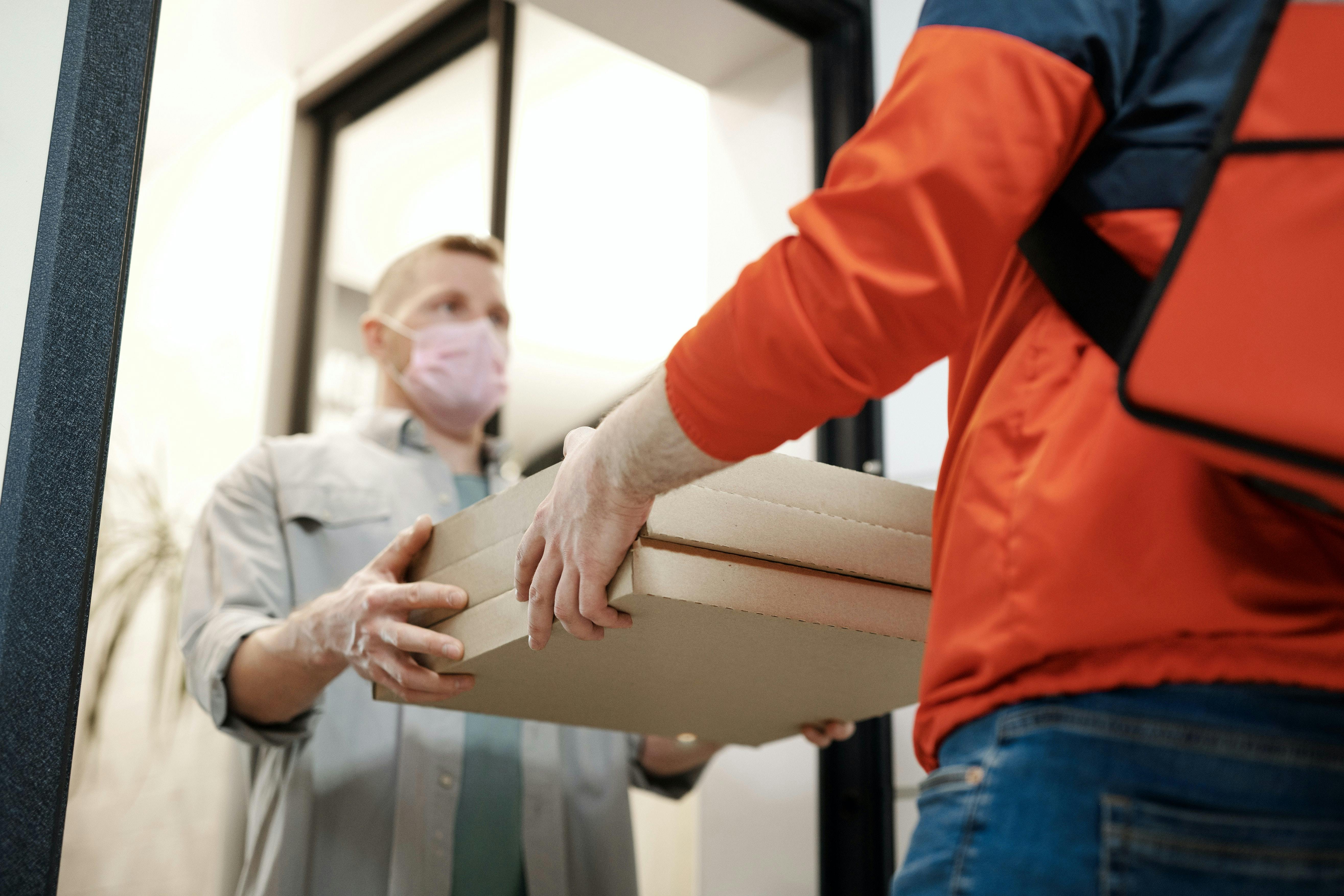 Delivery person handing a man three boxes of pizza