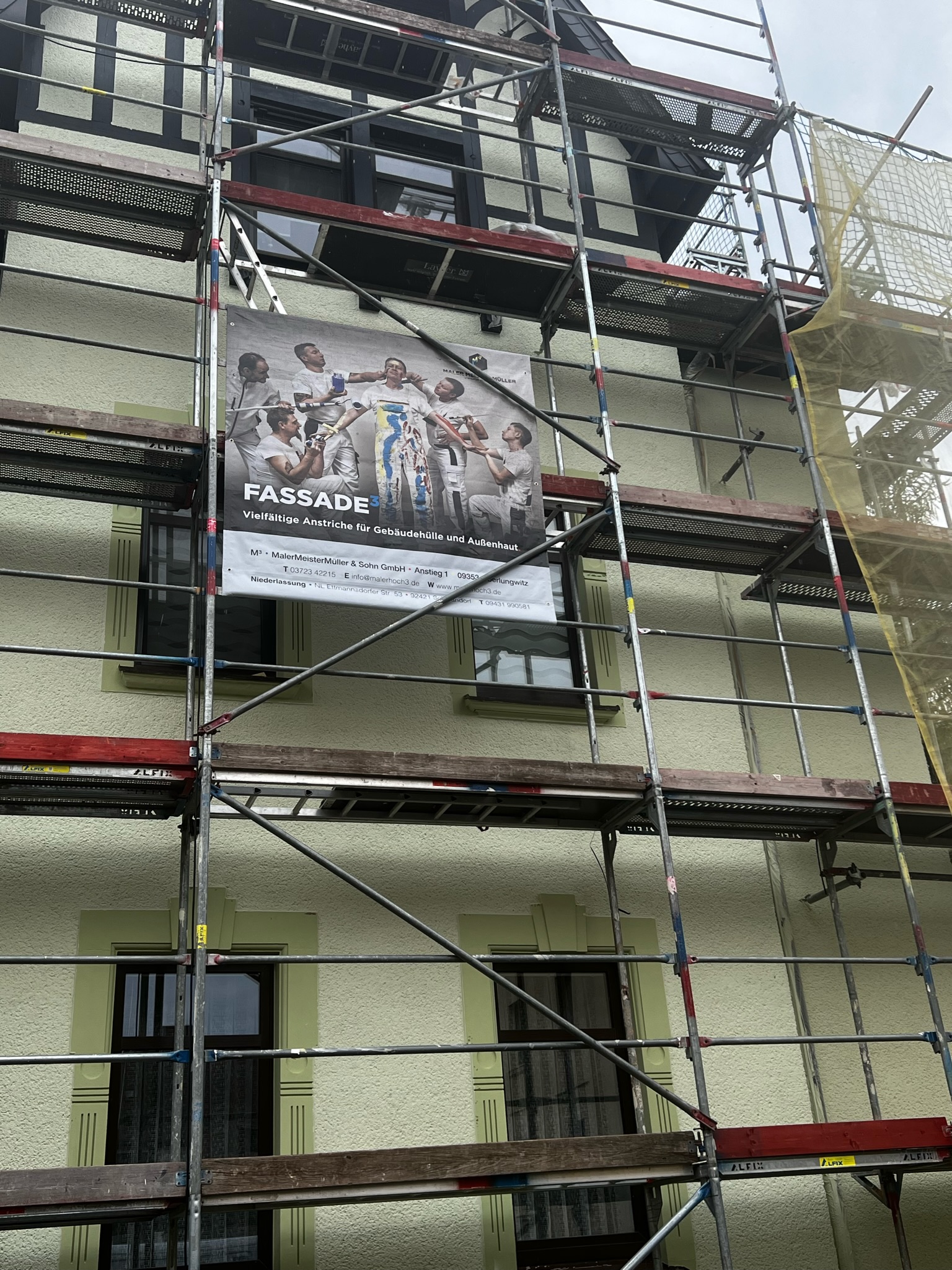 Fassadenarbeiten an einem Haus mit einem Plakat von Malermeister Müller uns Sohn. Fassadenarbeit 