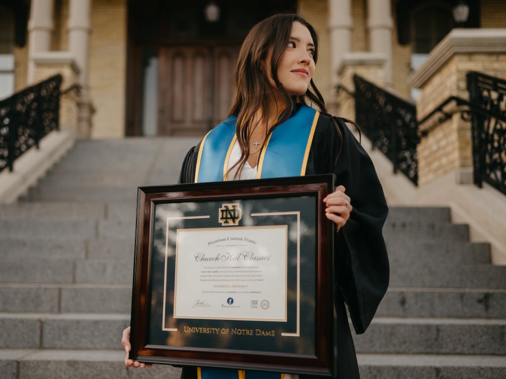 Graduate holding framed diploma