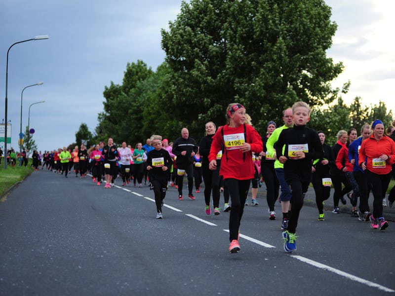 Participants in the 5 km race running down road Engjavegur