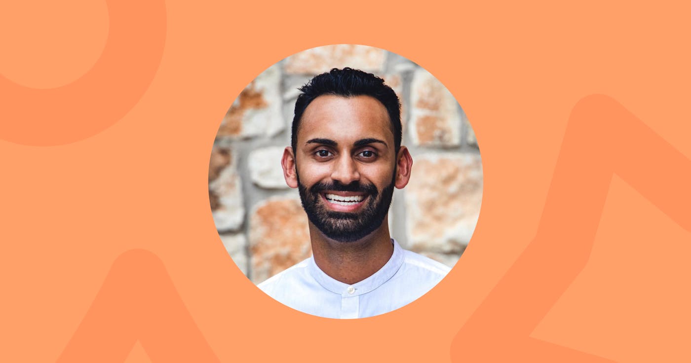 Headshot. Dentist and entrepreneur Dr. Avi Patel, wearing a white button-up collarless shirt smiling in front of a stone wall.