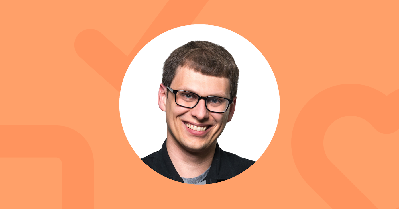 Headshot. Mike, an Executive Editor for a productivity publisher, wearing dark framed glasses and smiling in front of a seamless white background.